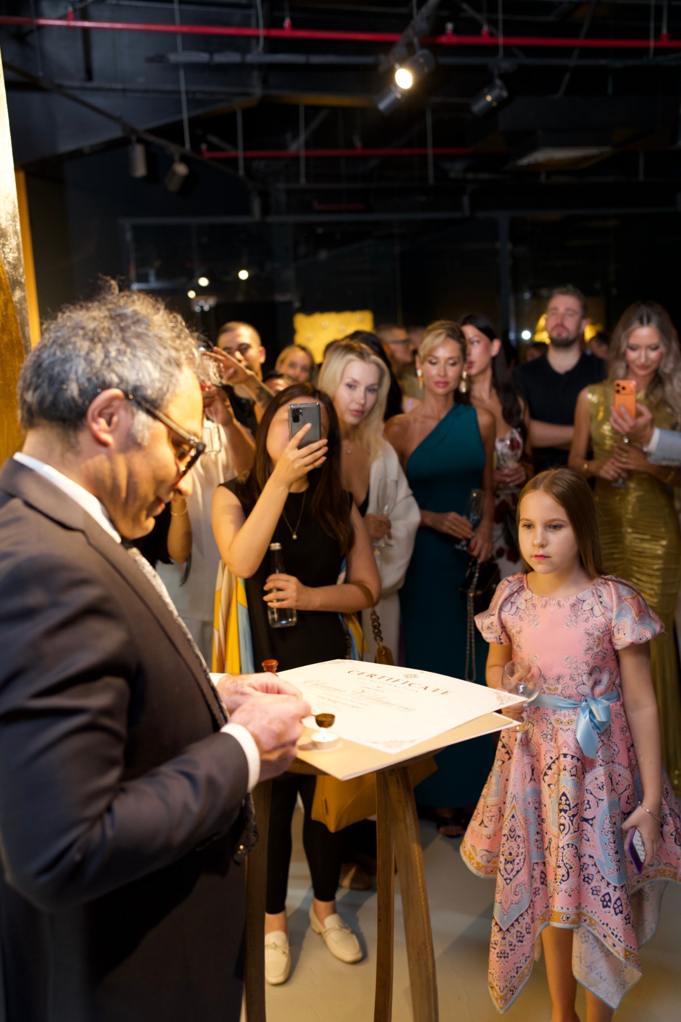 A certificate being sealed with wax while guests watch