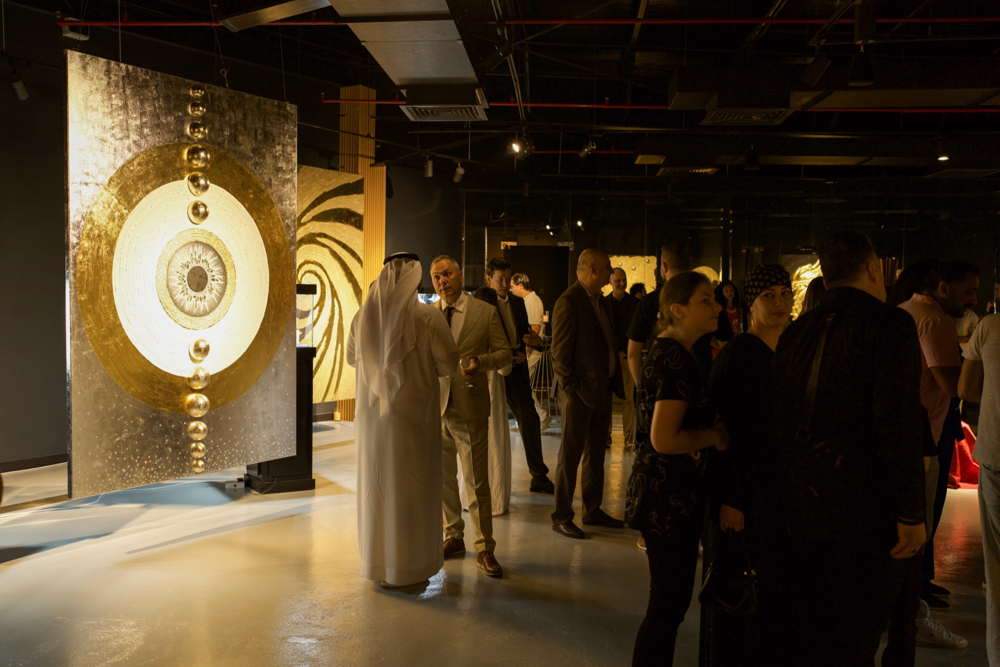 Gallery hall with a large gold-leaf artwork and guests at the gala