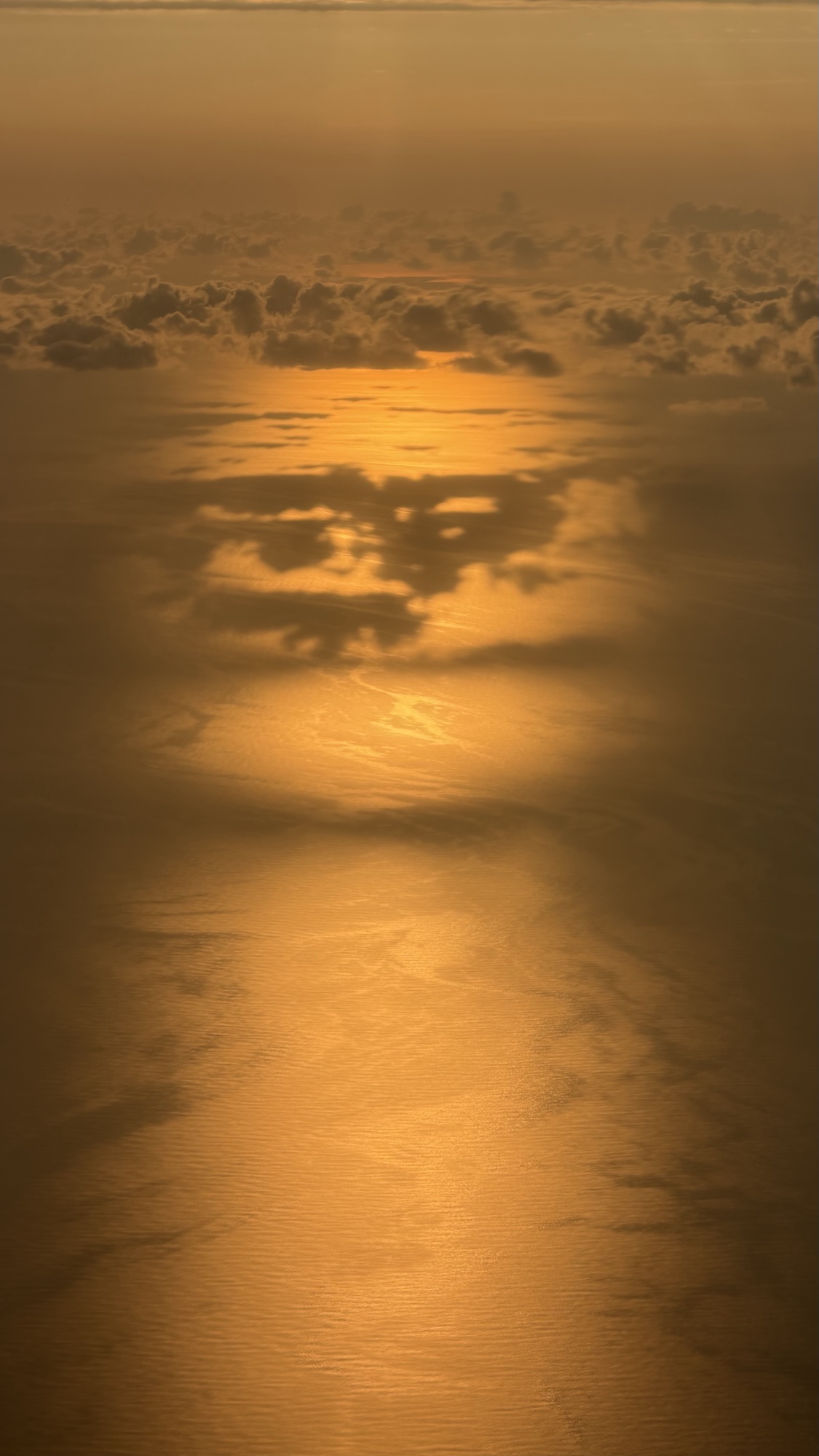 Golden sunset over the sea seen from above the clouds