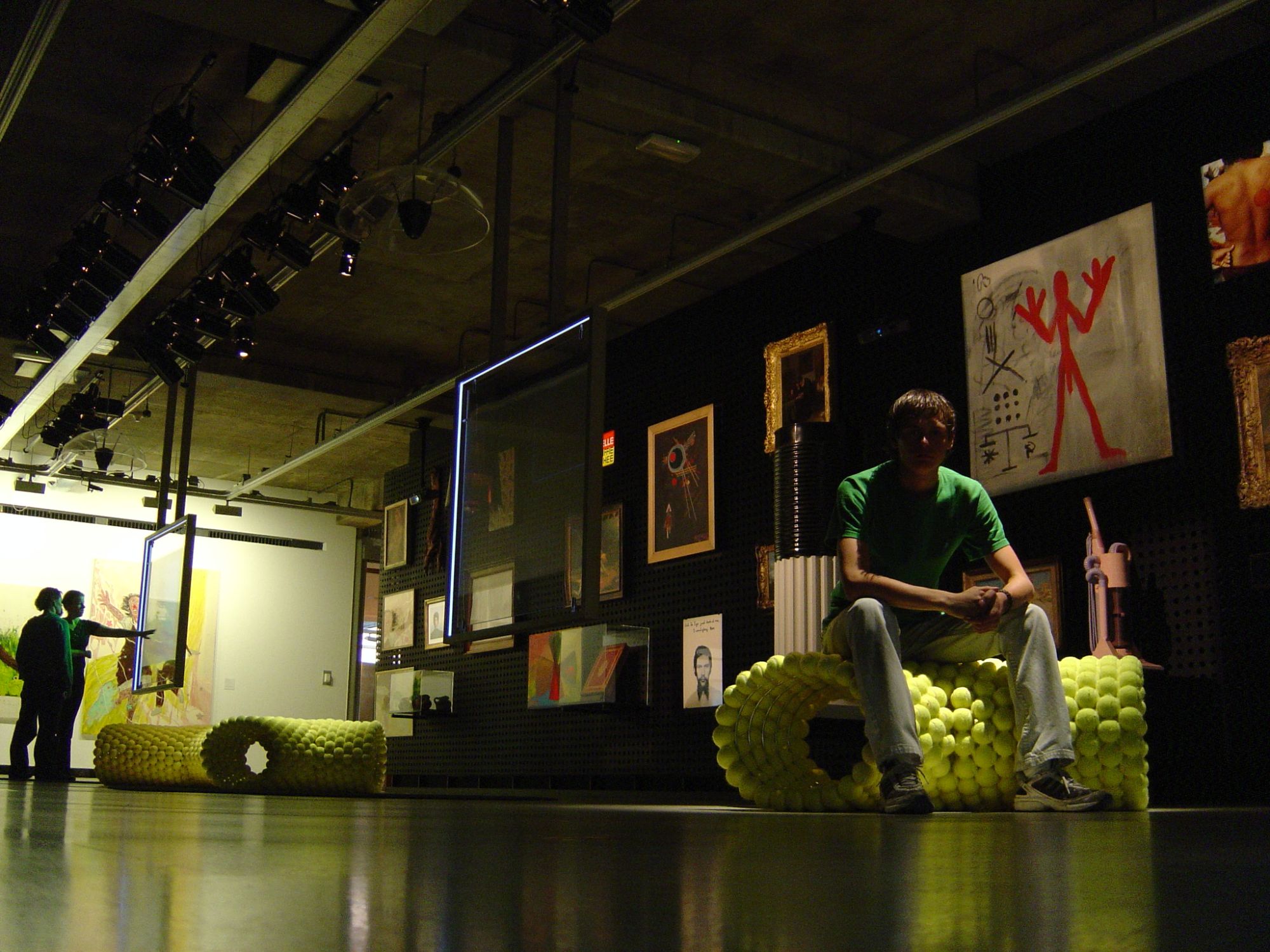 Young Roman sitting on a bench made of tennis balls in a gallery