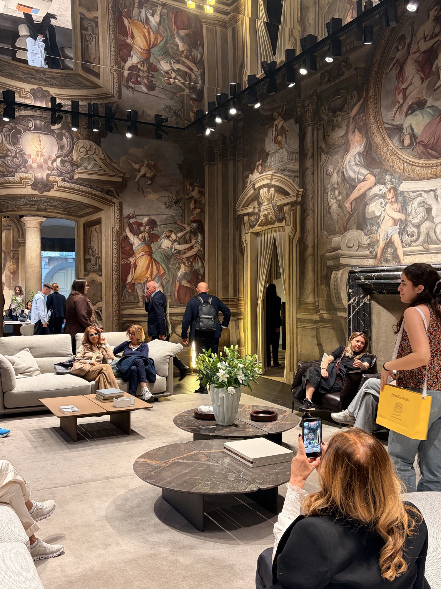 Exhibition stand with frescoed walls and a white sofa at Salone del Mobile