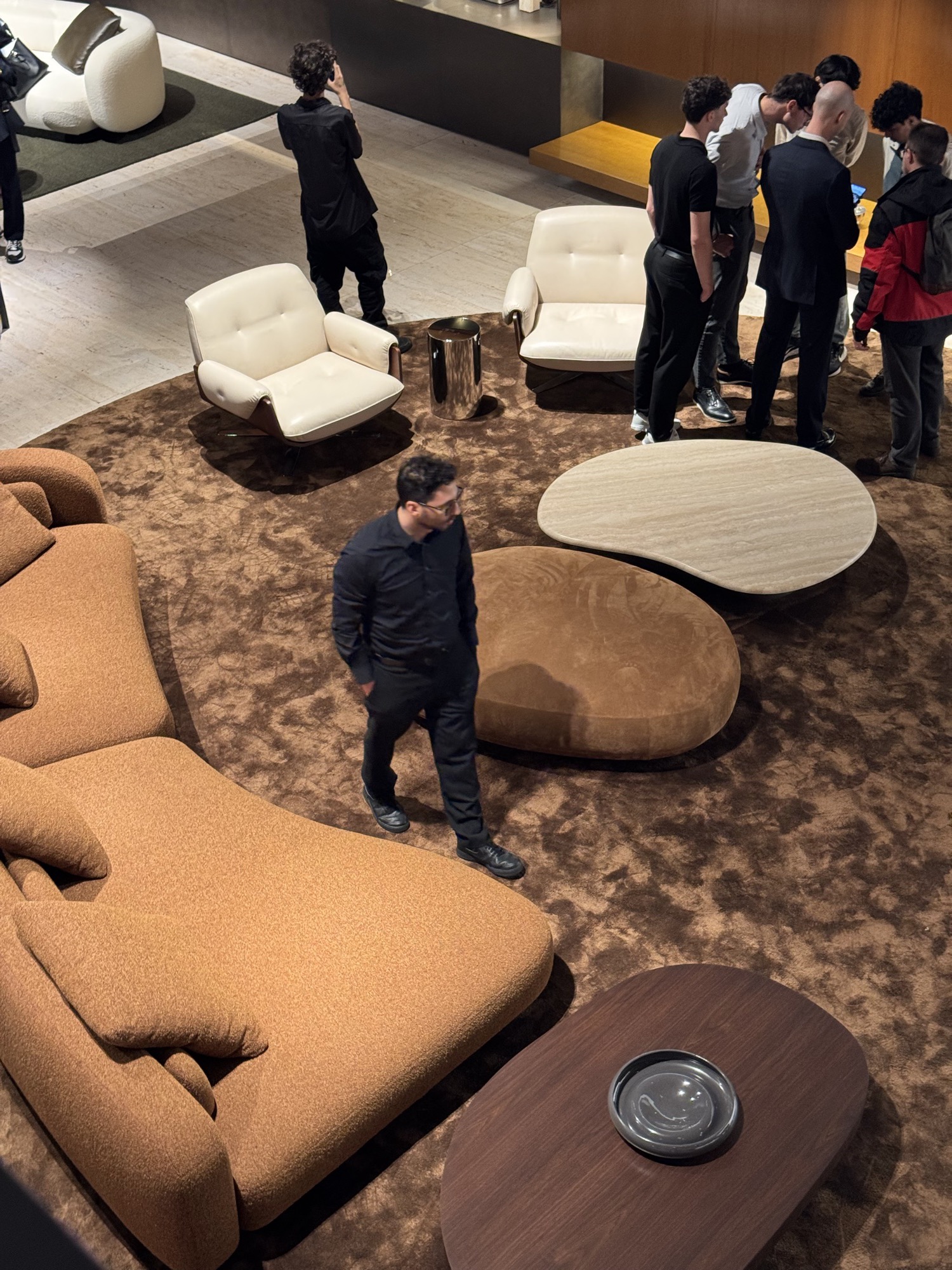 Furniture stand seen from above: terracotta sofa, pebble tables and visitors