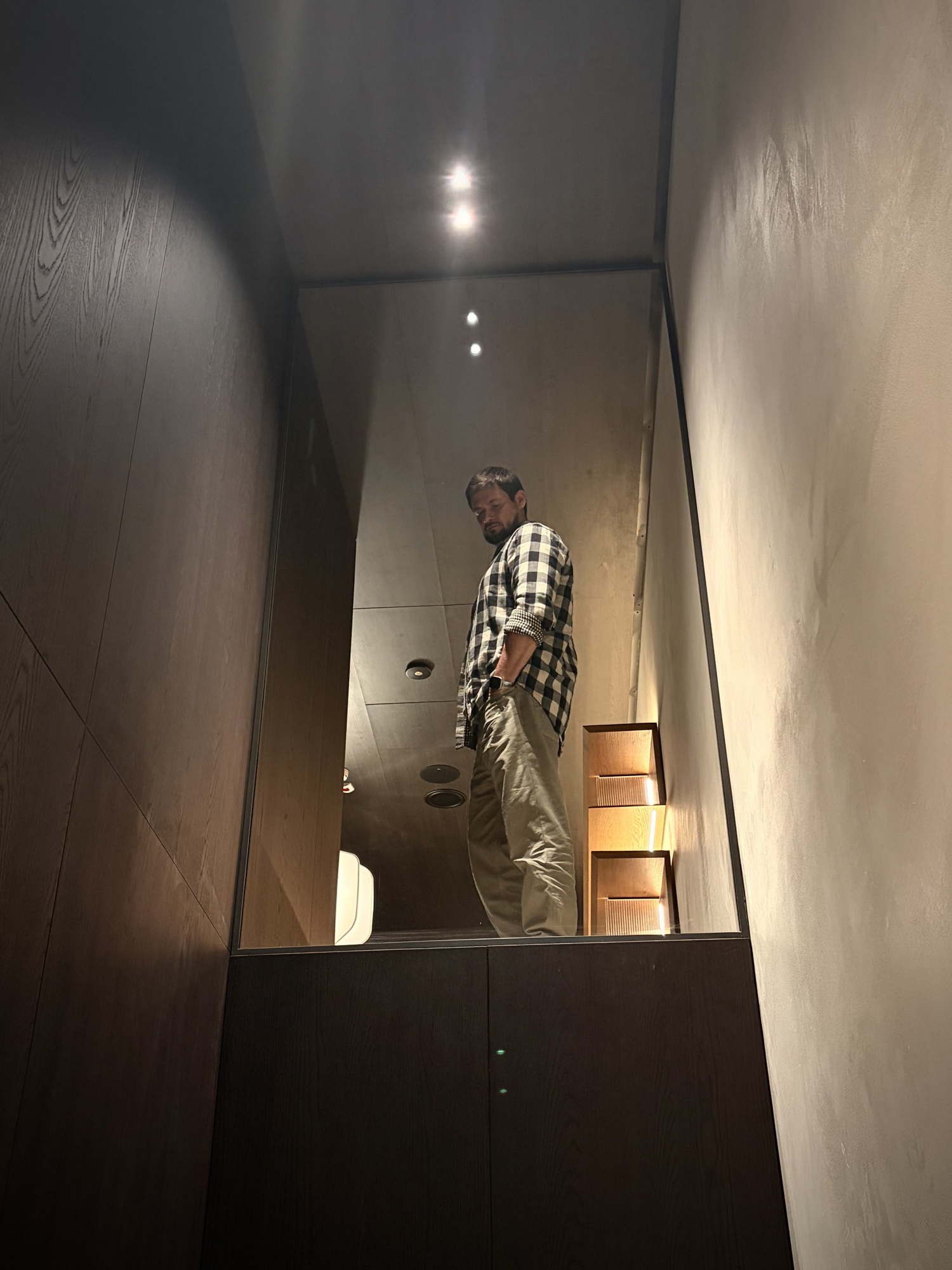 Roman Chertkov reflected in a mirrored niche of a dark wood cabinet