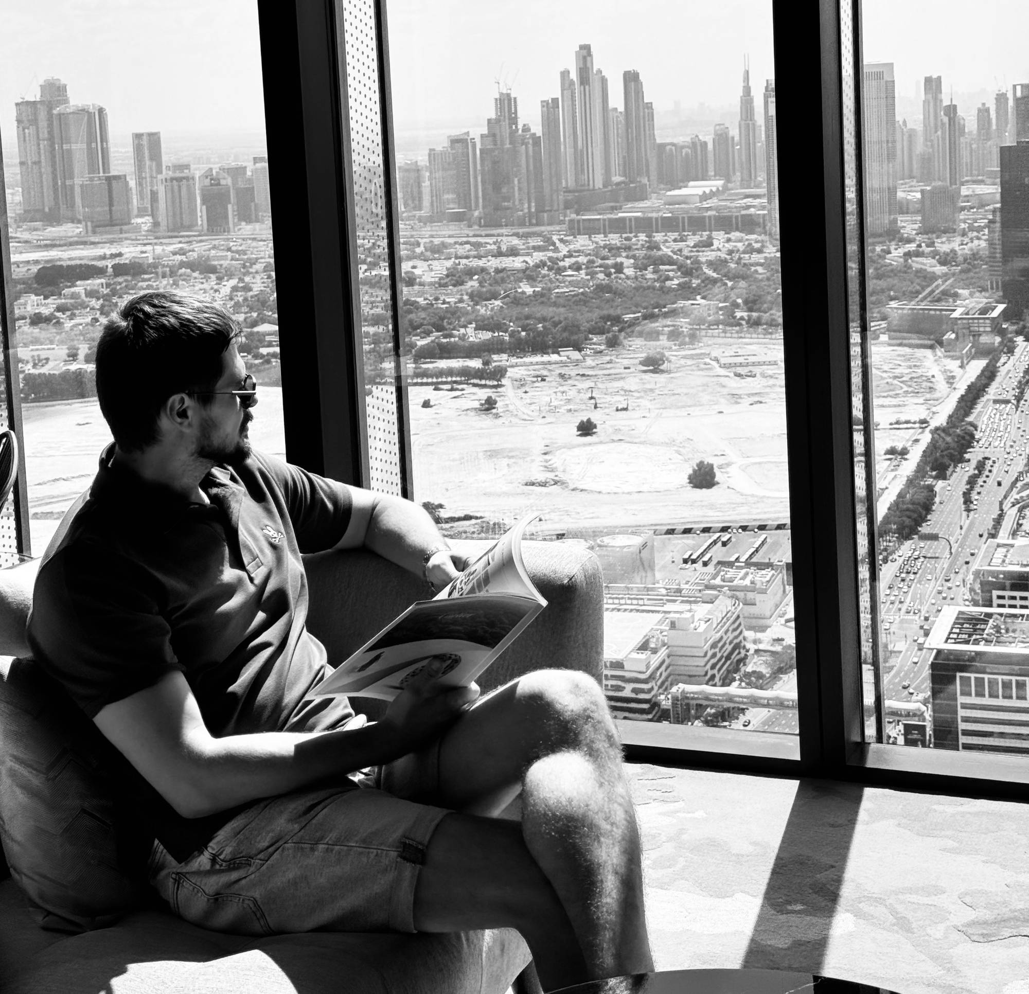 Roman Chertkov reading a magazine in an armchair by a window high above Dubai